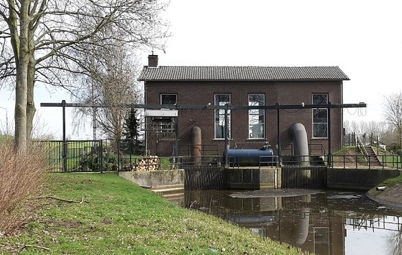 Historisch gemaalgebouw aan een watergang in een polderlandschap, symbool voor het eeuwenoude peilbeheer in Nederland.